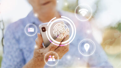 Mulher idosa branca de blusa azul segurando um celular olhando para ele, com ícones em branco pela imagem, e no centro a imagem de uma digital